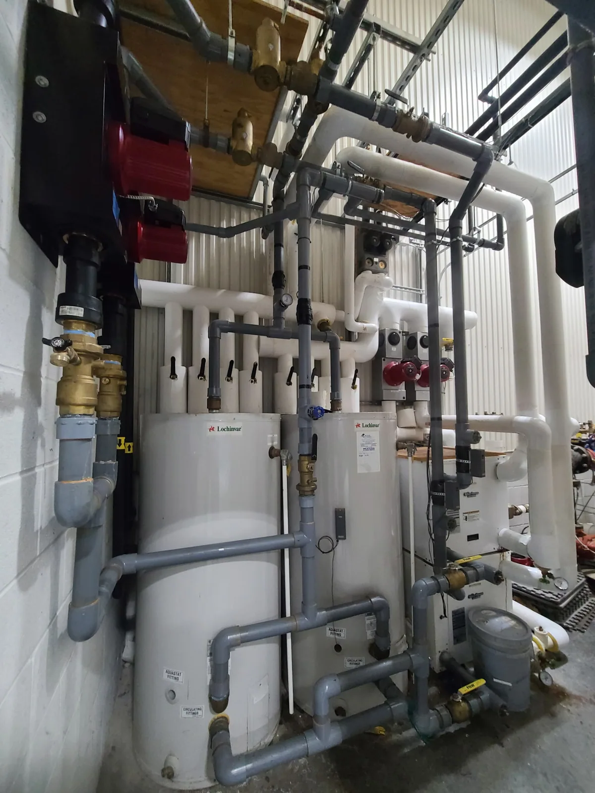 Commercial mechanical room with Lochinvar boilers, circulation pumps, insulated piping, and overhead distribution — 4th Gen install.