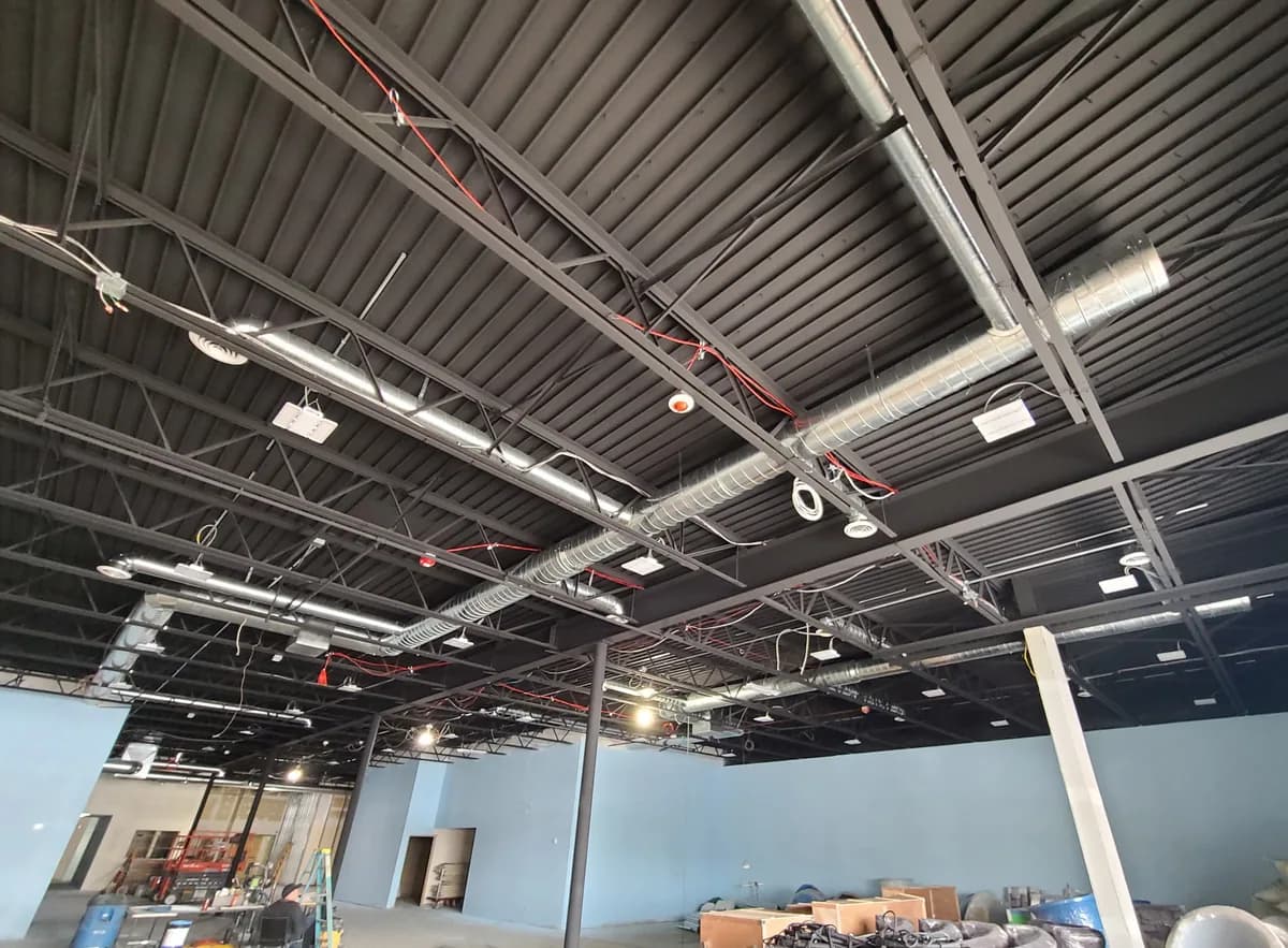 Exposed spiral duct runs and branch ducting in a commercial buildout — 4th Gen air distribution work.