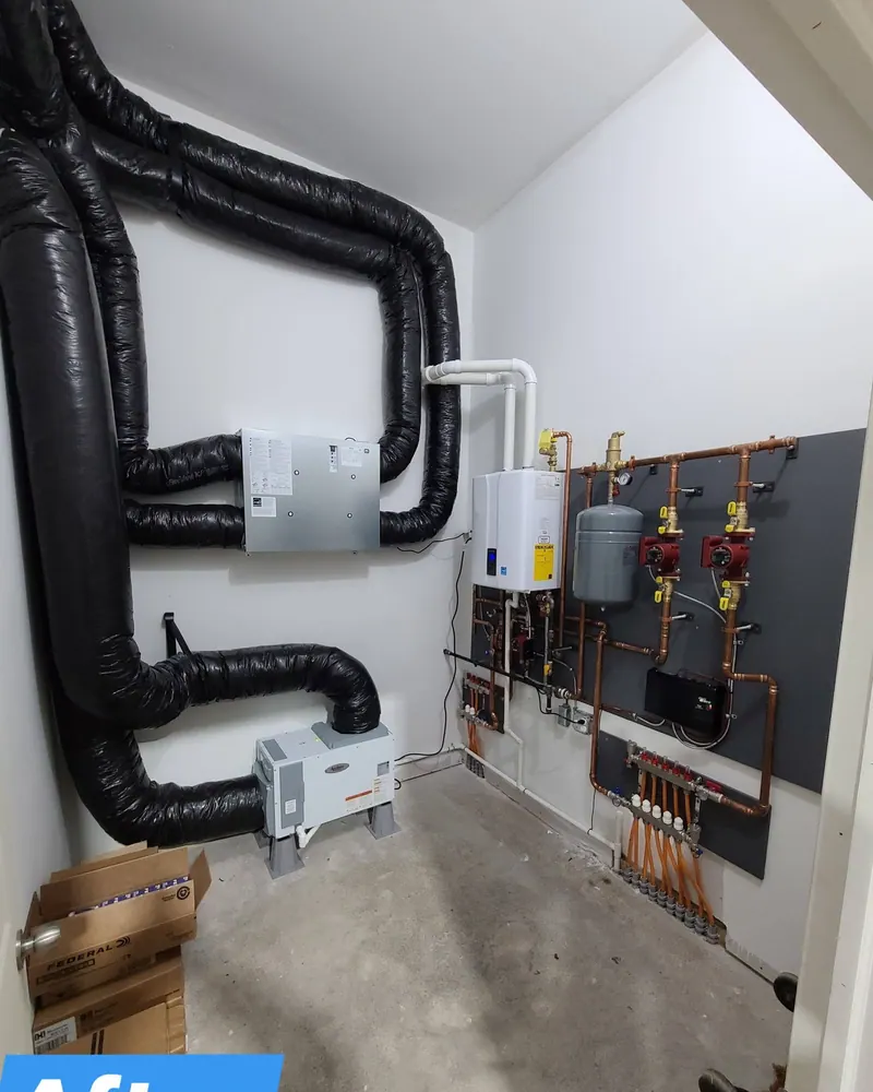Finished mechanical room — dual air handlers, tankless boiler, expansion tank, Taco circulator pumps, and copper hydronic distribution manifold.