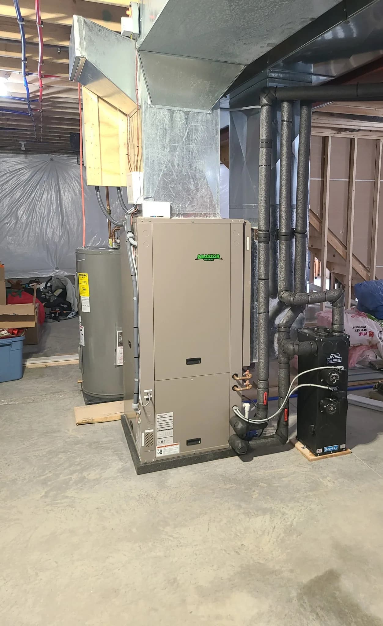 GeoStar geothermal heat pump alongside a high-efficiency tankless boiler and electric water heater in an unfinished Rochester basement — 4th Gen Mechanical install.