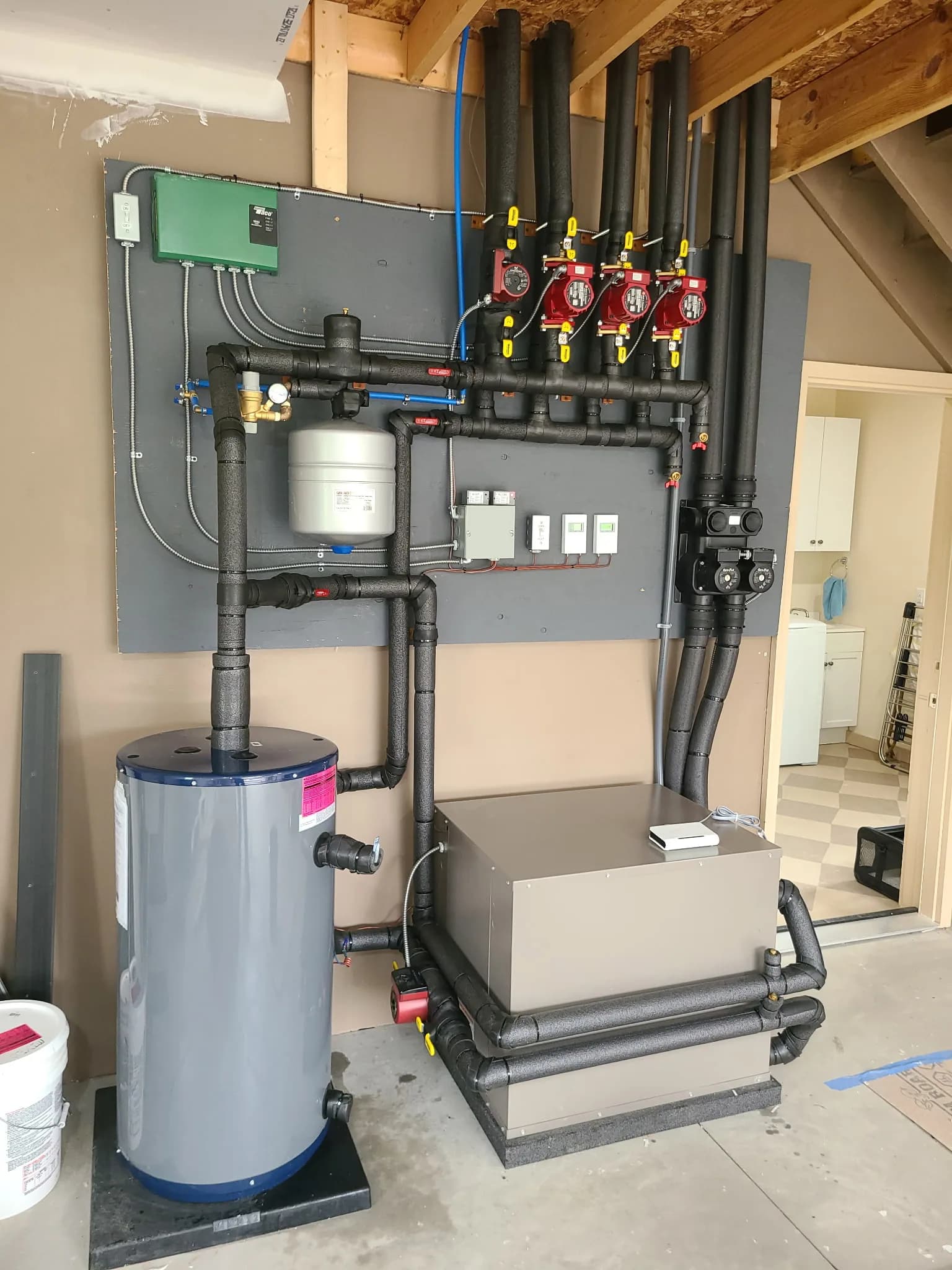 GeoStar geothermal heat pump with buffer tank, multiple circulator pumps, and insulated hydronic piping for a multi-zone install.