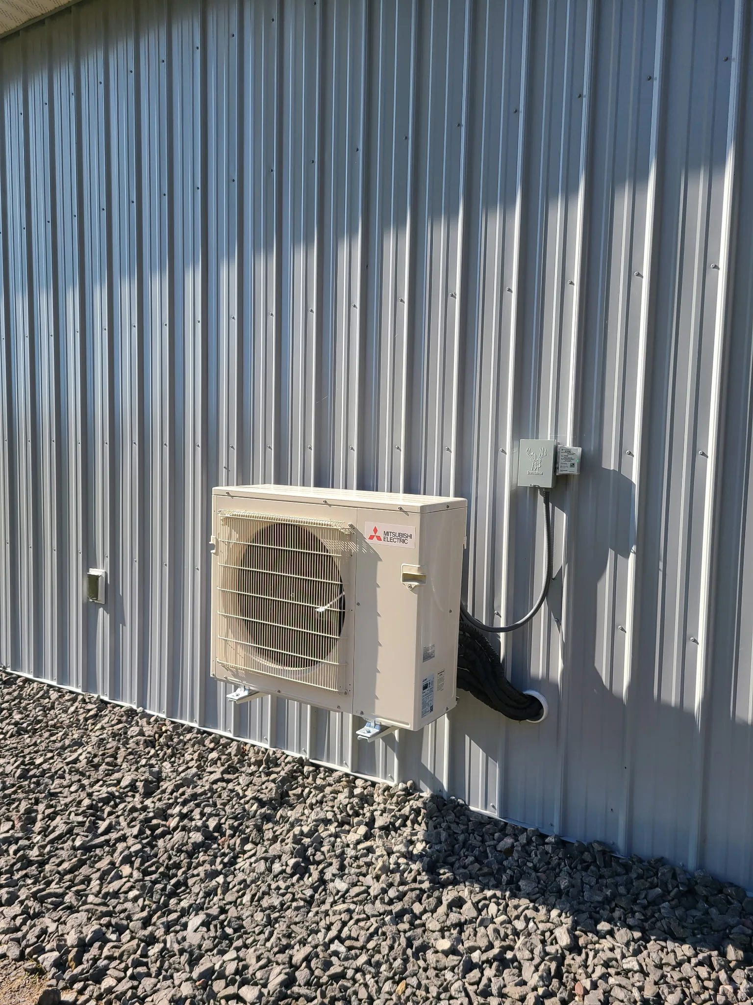 Mitsubishi Electric outdoor heat pump condenser mounted on the exterior of a Rochester building — 4th Gen Mechanical install.