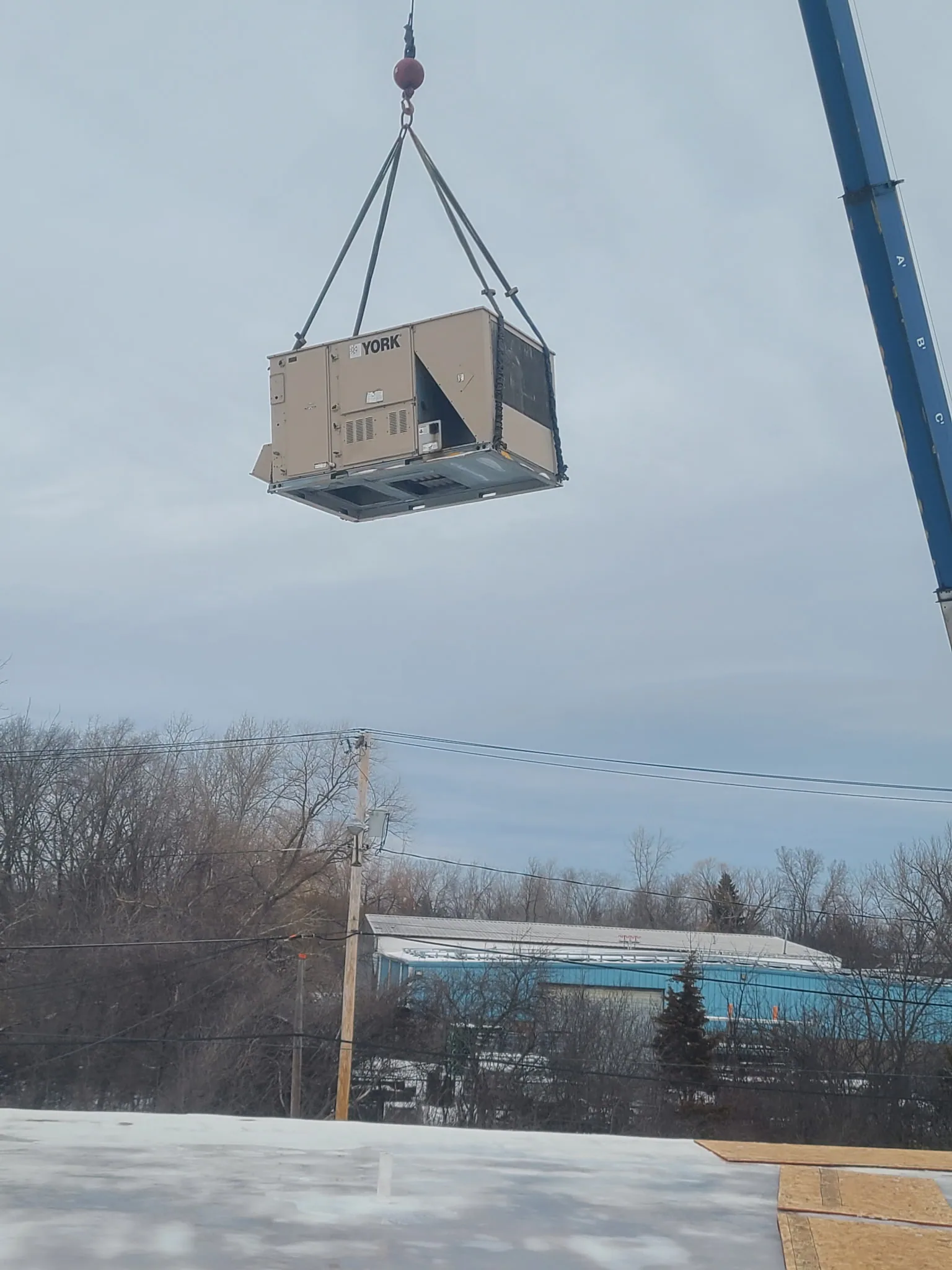York packaged rooftop unit being lifted by crane onto a commercial building — 4th Gen Mechanical install.