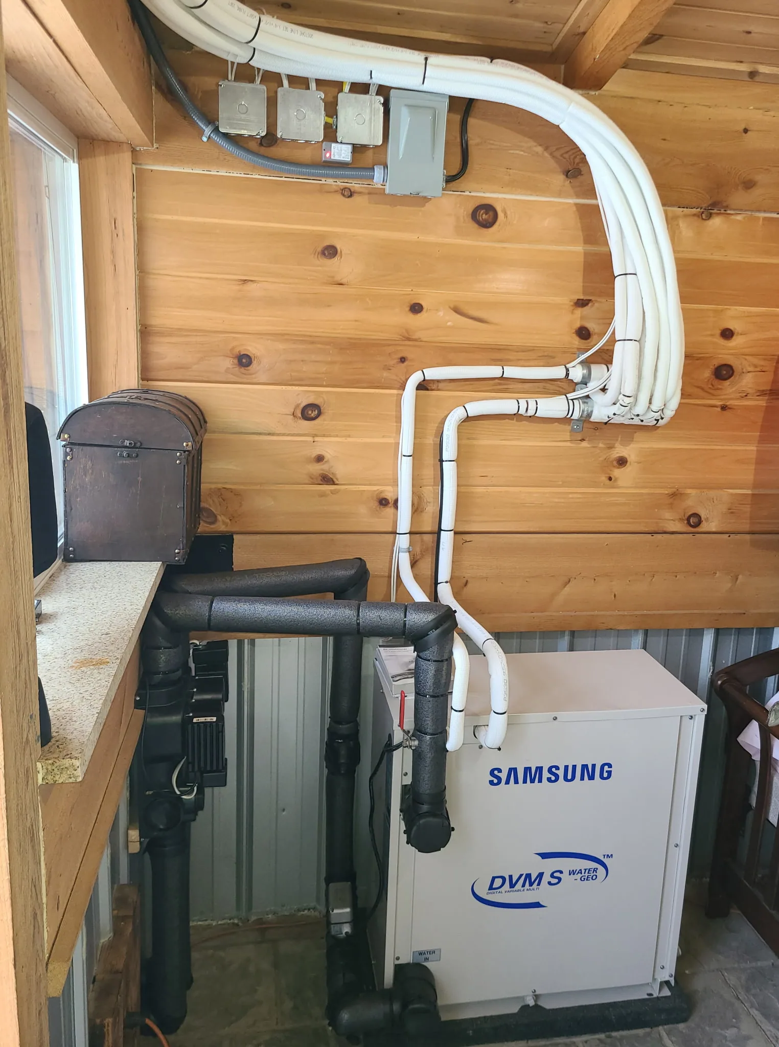 Samsung DVM S Water-GEO geothermal install in a finished wood-paneled mechanical space — 4th Gen build.